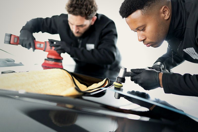 Two MAX WAX technicians machine polishing a car